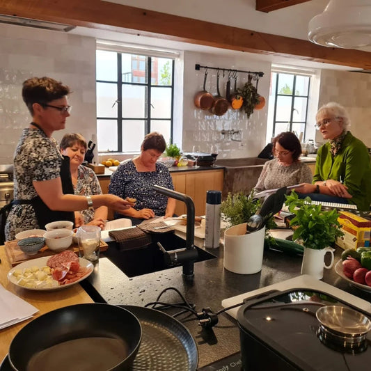 Group of people in a kitchen setting, preparing food.