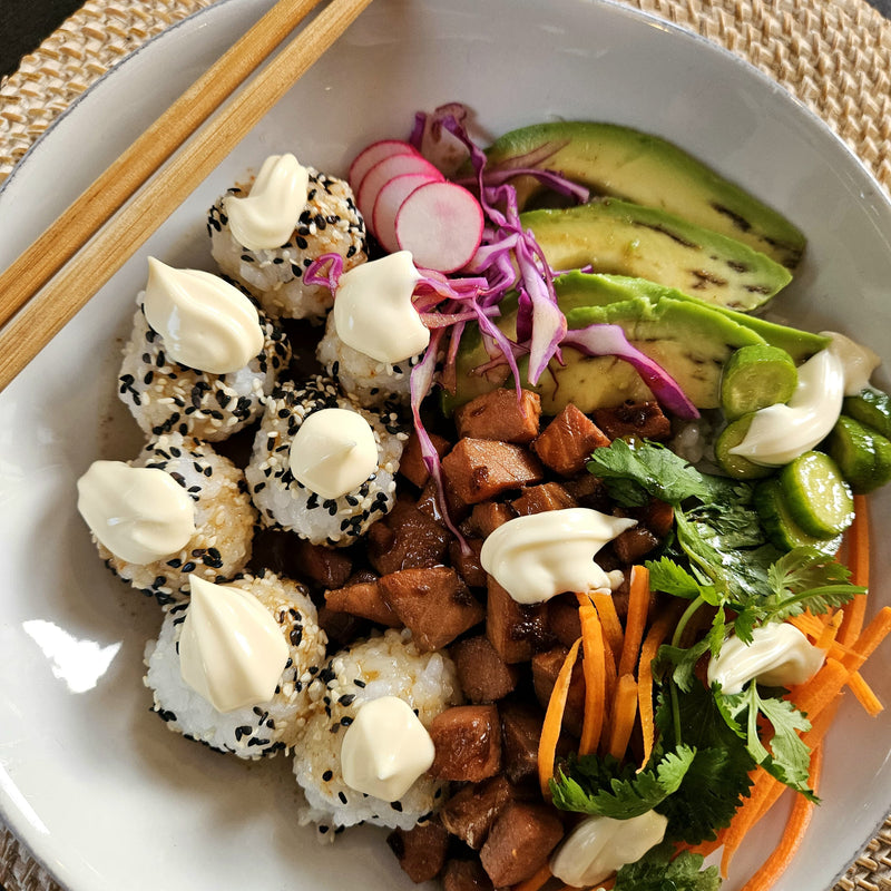 Plated dish with sushi, vegetables, and wasabi on a white plate.